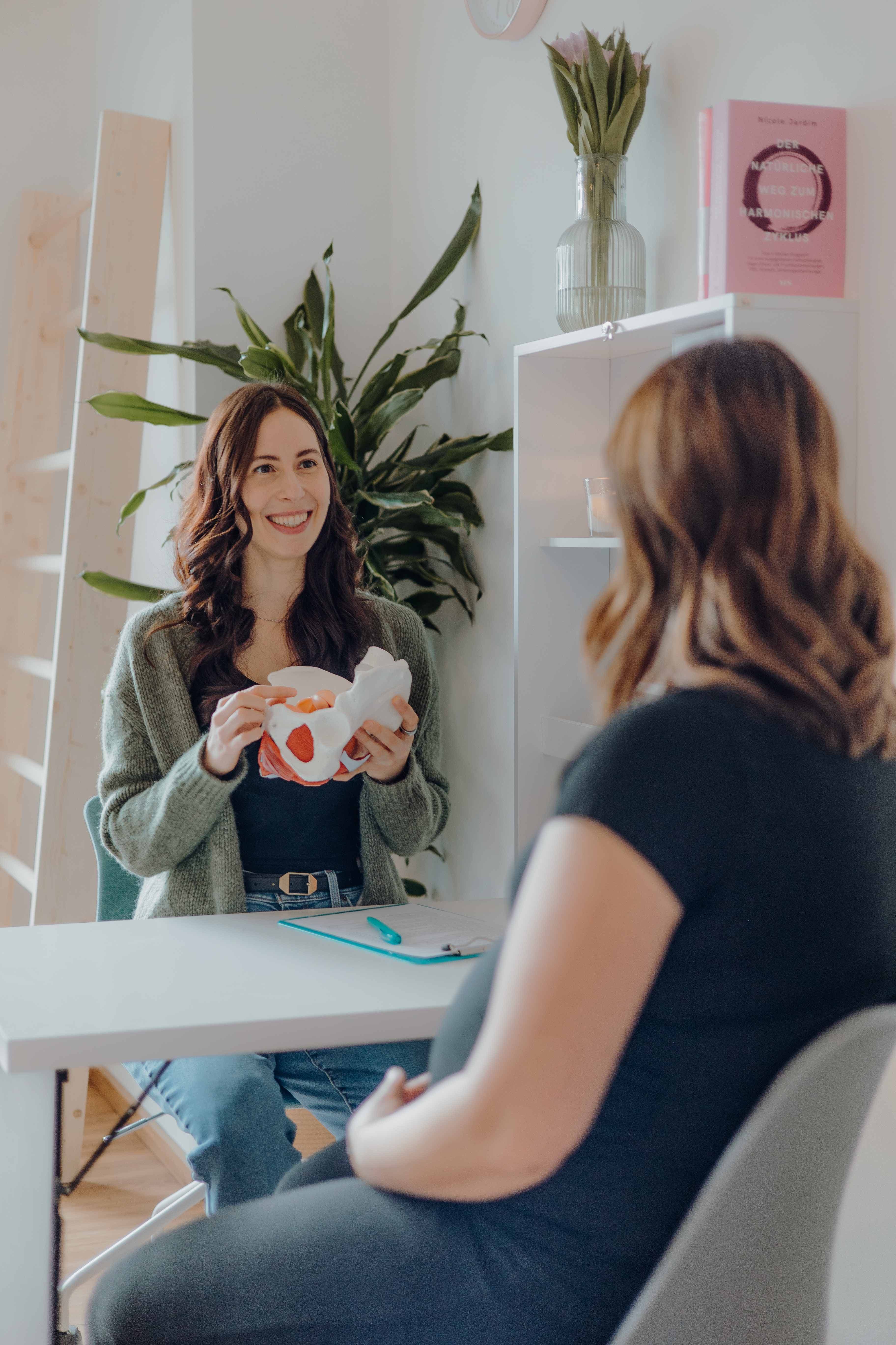 Therapeutin hilft Patientin bei Dehnübung auf der Matte