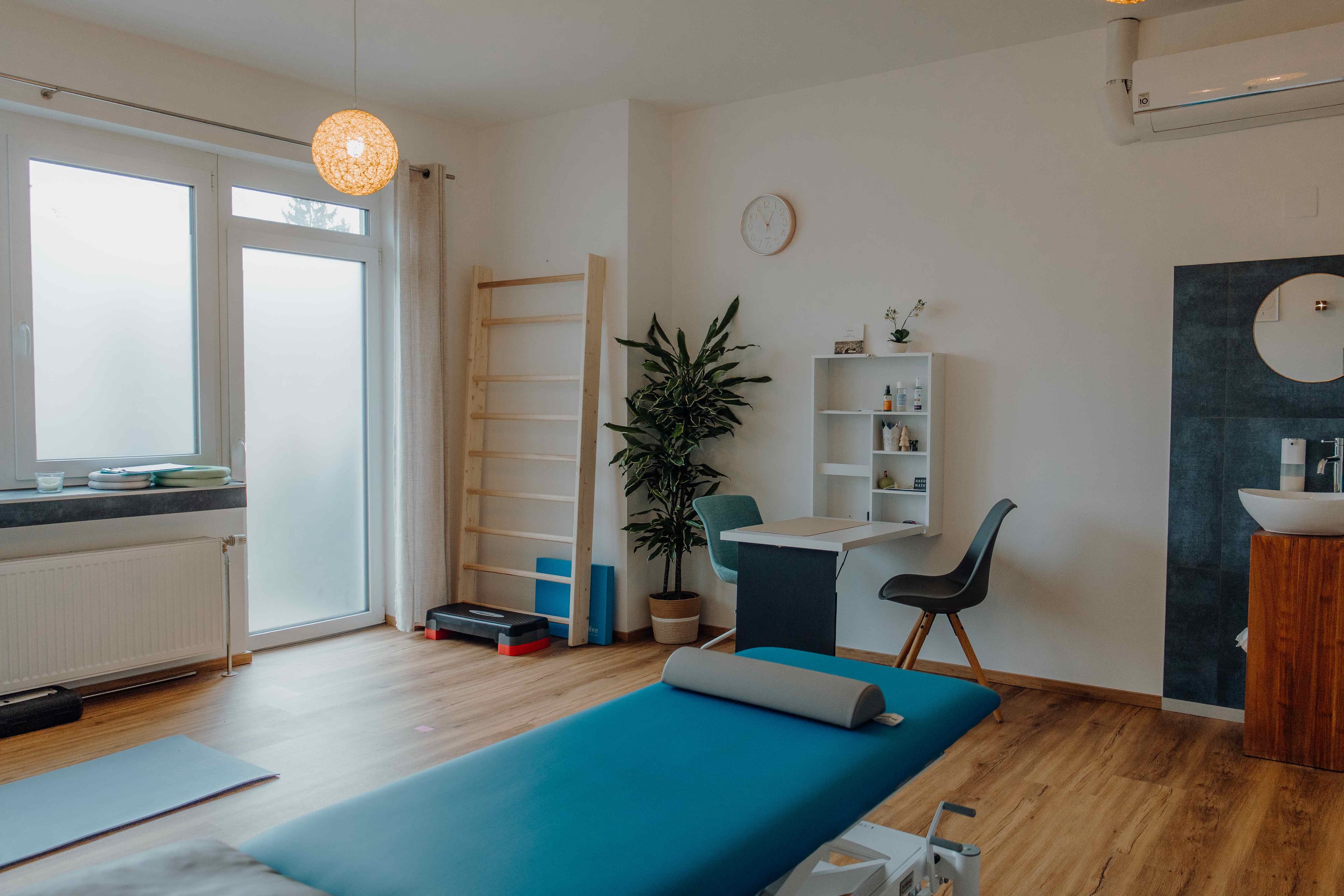 Behandlungsraum mit blauer Therapieliege und Yogamatte